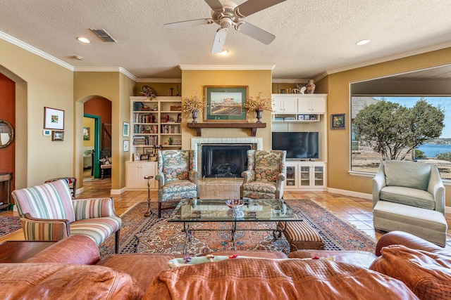 4204 Bluff View Dr, Granbury, TX 76048 - living room with tile patterned flooring, crown molding, arched walkways, ceiling fan, and visible vents