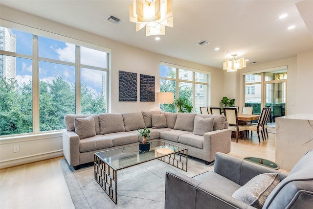 living room with a chandelier, recessed lighting, light wood finished floors, and baseboards