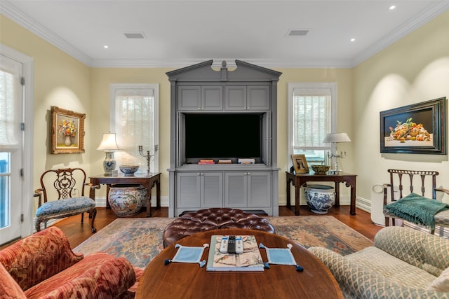 living room featuring wood finished floors, ornamental molding, and visible vents