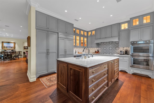 kitchen with backsplash, a sink, gray cabinets, and double oven