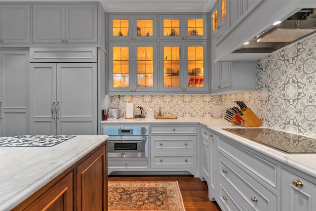 kitchen featuring decorative backsplash, black electric cooktop, paneled fridge, stainless steel oven, and extractor fan