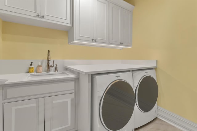 laundry room featuring a sink, cabinet space, washing machine and dryer, and baseboards