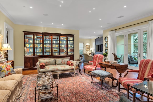 living room featuring visible vents, baseboards, ornamental molding, wood finished floors, and recessed lighting
