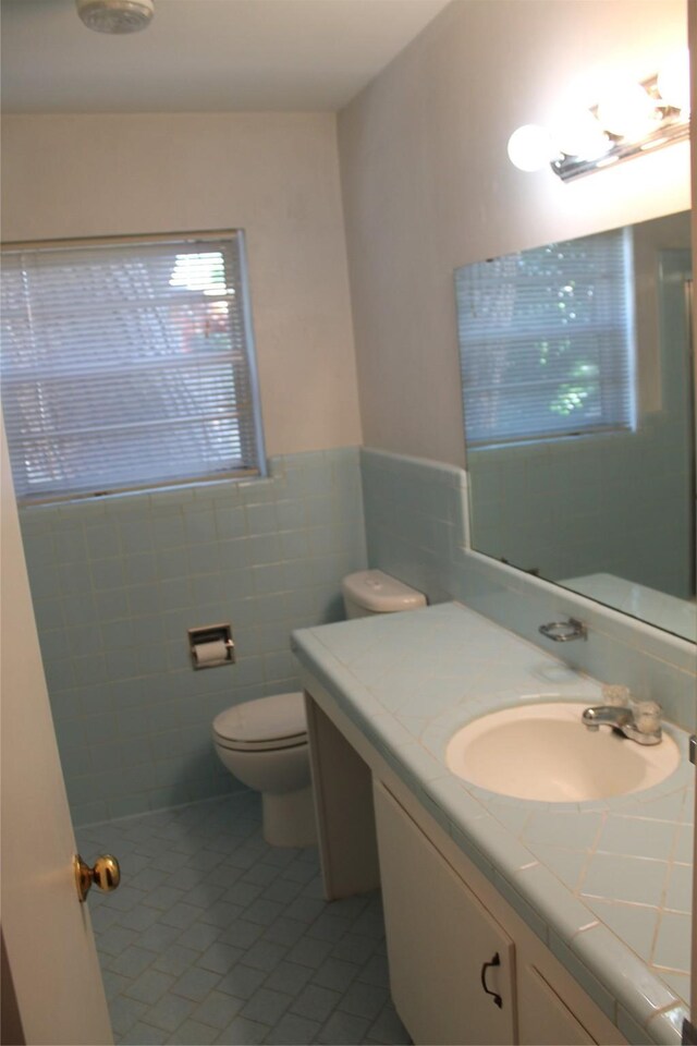 4605 Avoca St, Fort Worth, TX 76132 - bathroom featuring tile patterned floors, toilet, vanity, tile walls, and wainscoting