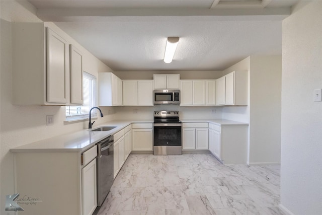 1318 Burger St, Abilene, TX 79603 - kitchen featuring stainless steel appliances, light marble finish flooring, a sink, light countertops, and white cabinets