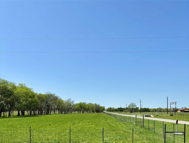 view of home's community with fence, a rural view, and a yard
