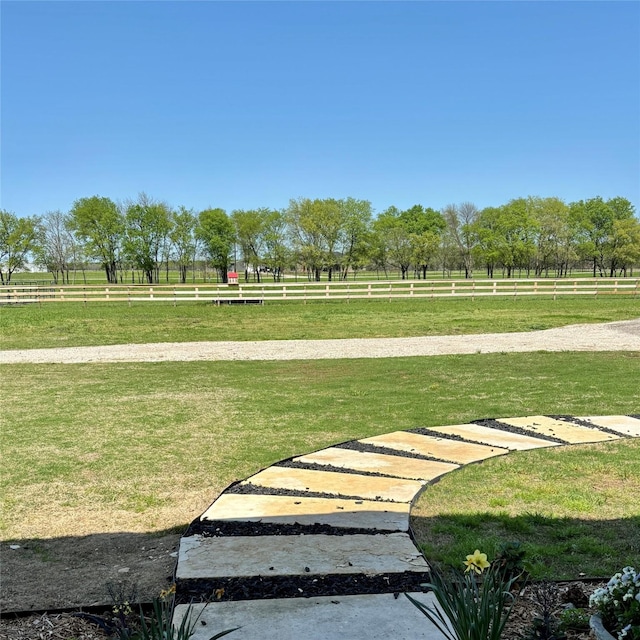 view of home's community featuring a lawn, fence, and a rural view