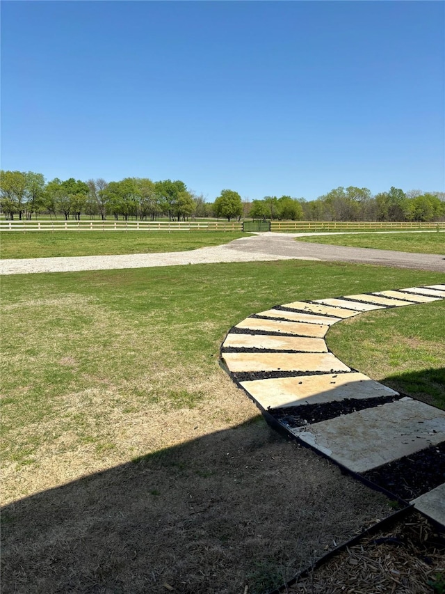 view of home's community with a lawn, fence, and a rural view