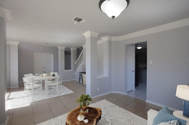 tiled dining room featuring ornate columns, crown molding, baseboards, and stairs