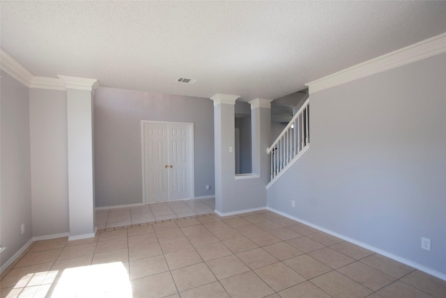 spare room with a textured ceiling, visible vents, light tile patterned flooring, ornamental molding, and stairs
