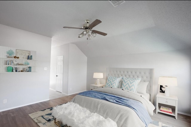 bedroom with visible vents, vaulted ceiling, wood finished floors, and baseboards