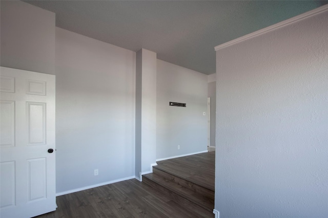 empty room with dark wood-style flooring and baseboards