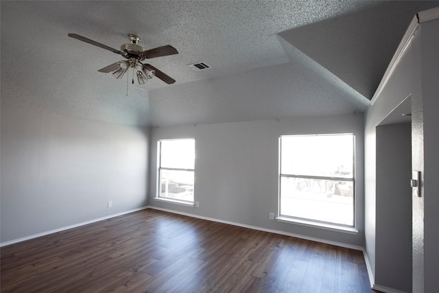 empty room featuring a ceiling fan, visible vents, vaulted ceiling, baseboards, and dark wood finished floors