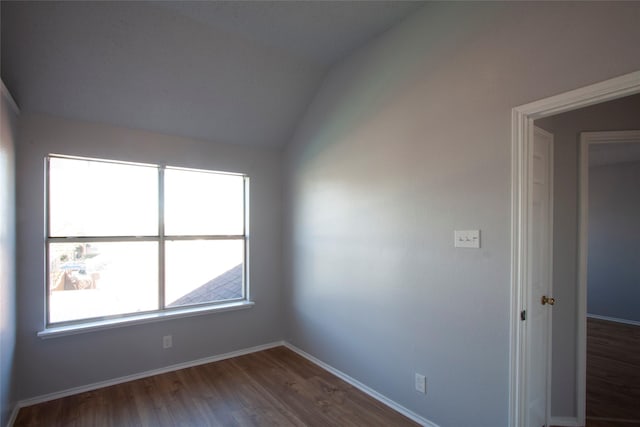 spare room featuring dark wood-style floors, vaulted ceiling, and baseboards