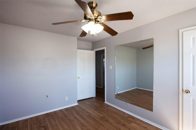 unfurnished bedroom with dark wood-style floors, baseboards, a ceiling fan, and a textured ceiling