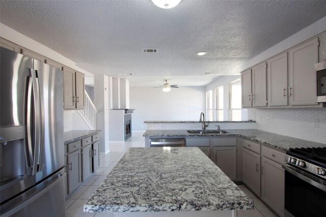 kitchen featuring a textured ceiling, a sink, ceiling fan, visible vents, and stainless steel appliances