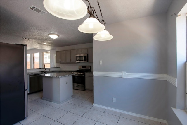 kitchen with light tile patterned flooring, visible vents, a kitchen island, and stainless steel appliances