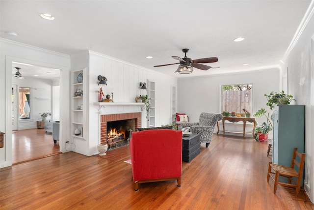 320 Eastwood Ave, Fort Worth, TX 76107 - living room with a ceiling fan, crown molding, built in shelves, wood finished floors, and a brick fireplace
