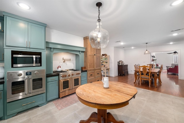 320 Eastwood Ave, Fort Worth, TX 76107 - kitchen featuring appliances with stainless steel finishes, green cabinetry, decorative backsplash, dark countertops, and hanging light fixtures