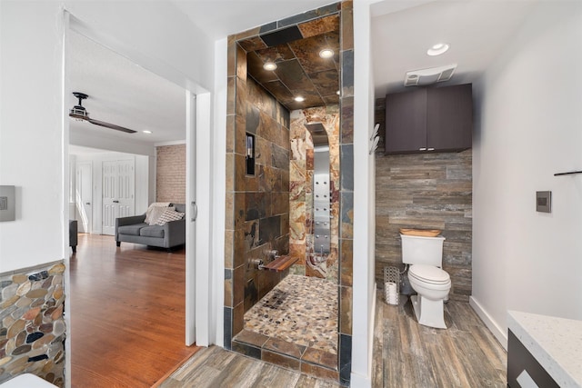 320 Eastwood Ave, Fort Worth, TX 76107 - full bathroom featuring wood finished floors, toilet, a walk in shower, ceiling fan, and tile walls
