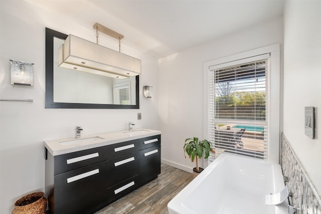 320 Eastwood Ave, Fort Worth, TX 76107 - bathroom with wood finished floors, a tub to relax in, double vanity, and baseboards