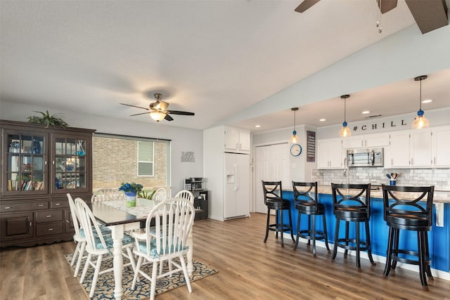 dining space featuring lofted ceiling, a ceiling fan, wood finished floors, and recessed lighting