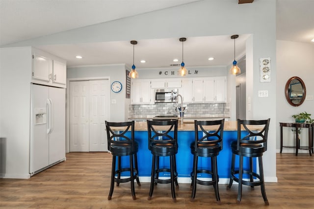 kitchen featuring white cabinets, decorative backsplash, white refrigerator with ice dispenser, and stainless steel microwave
