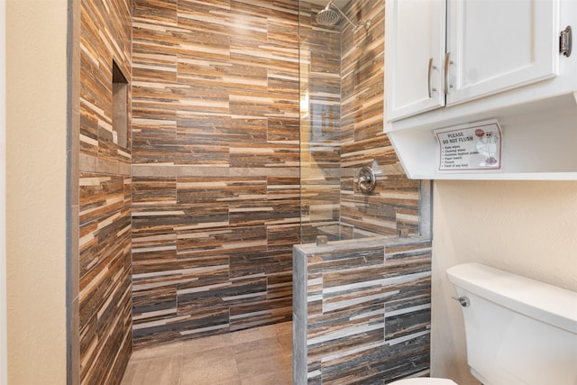 bathroom with a tile shower and toilet