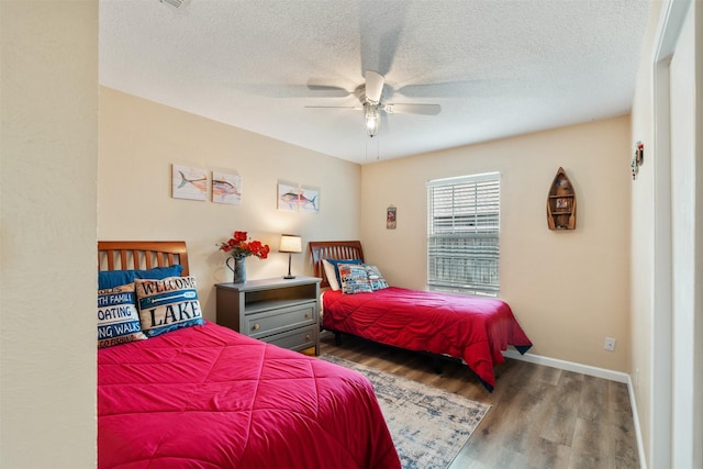 bedroom with wood finished floors, a textured ceiling, a ceiling fan, and baseboards