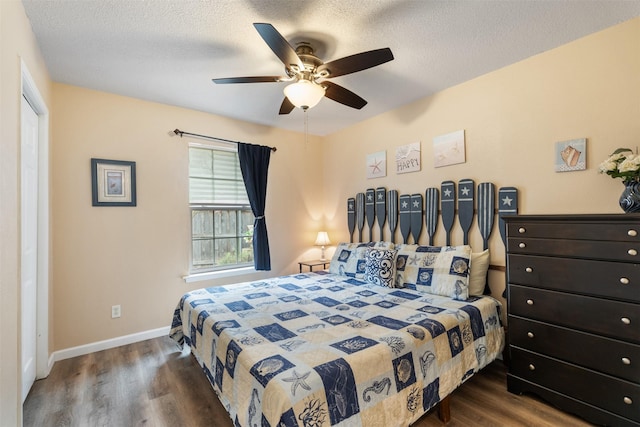 bedroom with a ceiling fan, baseboards, a textured ceiling, and dark wood finished floors
