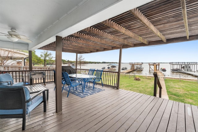 wooden terrace with a pergola, a lawn, a water view, outdoor dining area, and ceiling fan