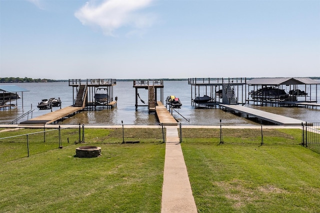 dock area with fence, an outdoor fire pit, a yard, and boat lift