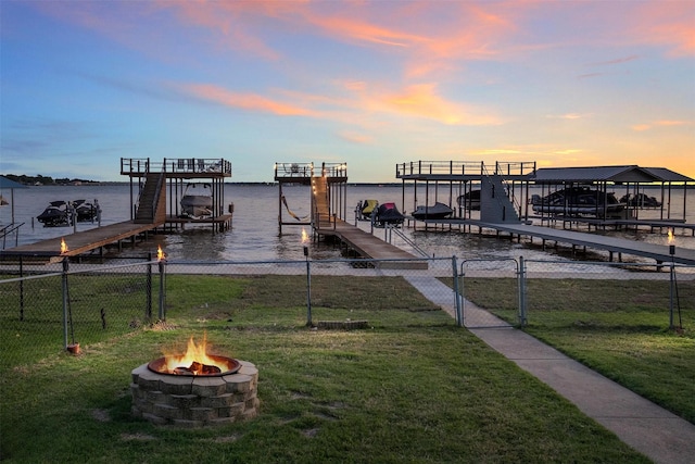 dock area with a fire pit, a yard, boat lift, and a water view