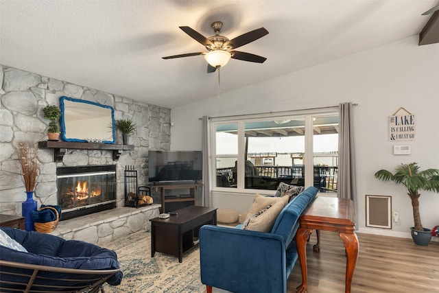 living room with vaulted ceiling, baseboards, a ceiling fan, wood finished floors, and a fireplace