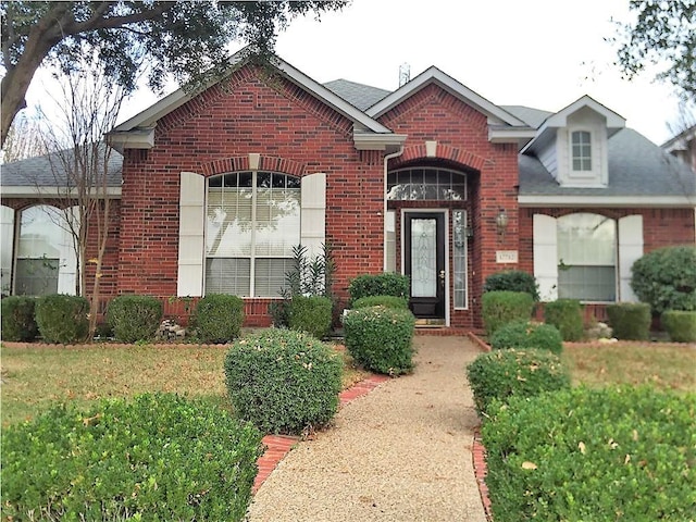 traditional home featuring a front yard and brick siding