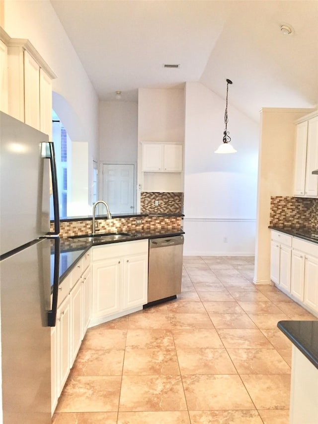 kitchen with vaulted ceiling, a sink, stainless steel appliances, visible vents, and decorative light fixtures