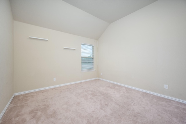 carpeted spare room with baseboards and lofted ceiling