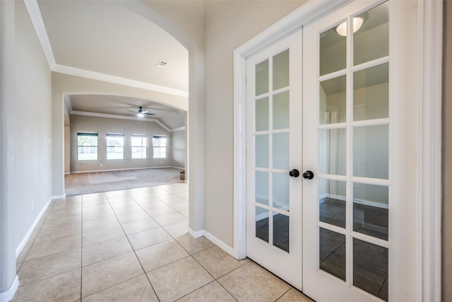hall featuring light tile patterned flooring, french doors, baseboards, arched walkways, and ornamental molding