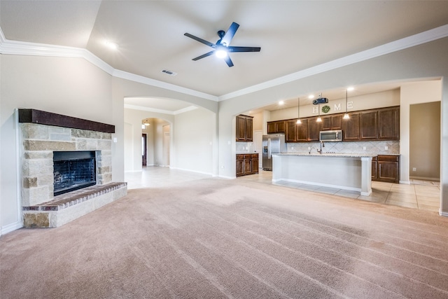 unfurnished living room featuring crown molding, baseboards, light colored carpet, visible vents, and ceiling fan