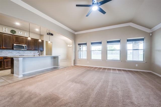 kitchen featuring stainless steel microwave, dark brown cabinets, ceiling fan with notable chandelier, and light carpet