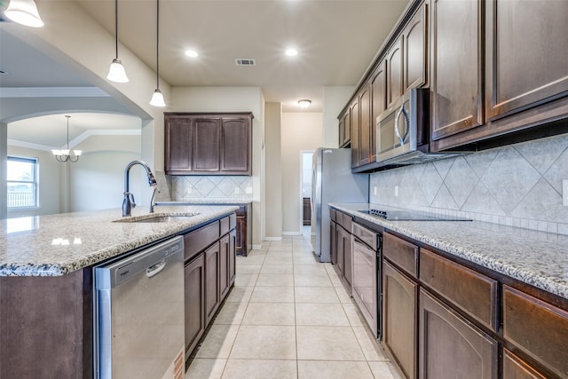 kitchen with stainless steel appliances, a sink, arched walkways, light stone counters, and visible vents