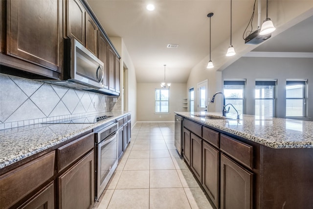 kitchen featuring light tile patterned floors, stainless steel appliances, backsplash, a sink, and light stone counters