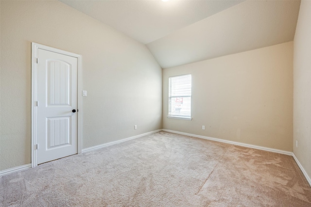 carpeted empty room with baseboards and lofted ceiling