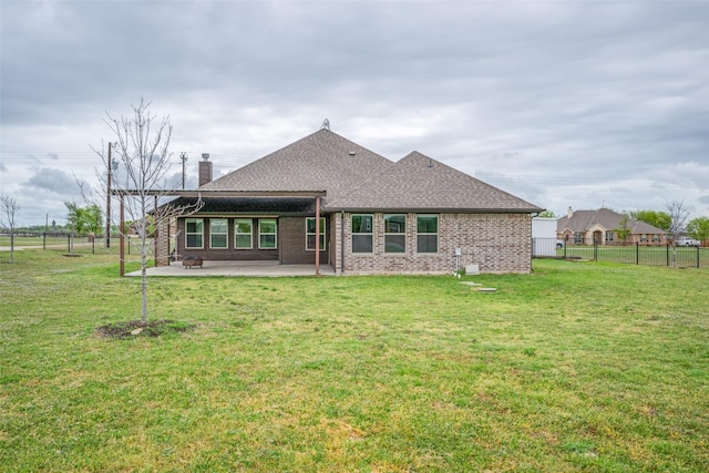 rear view of house with fence, a patio area, brick siding, and a yard