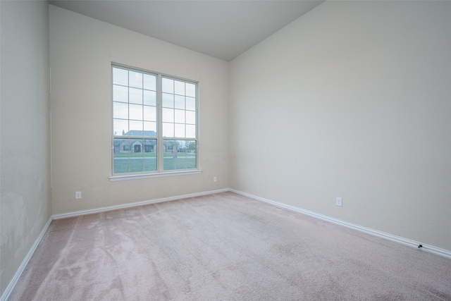 unfurnished room with baseboards, vaulted ceiling, and carpet