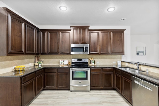 kitchen with appliances with stainless steel finishes, decorative backsplash, dark brown cabinetry, and dark stone countertops