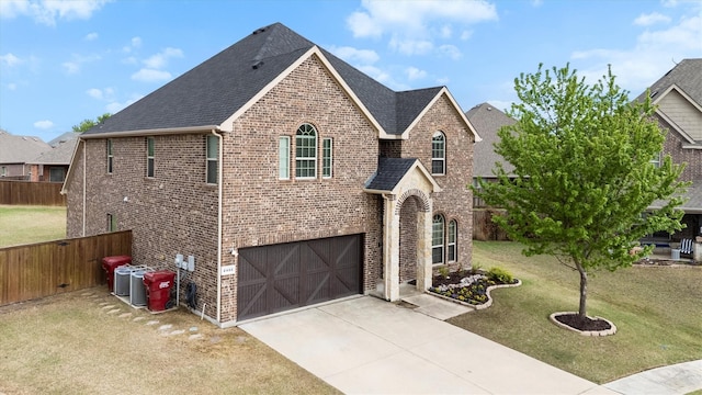 traditional-style home with brick siding, a garage, fence, and a front yard