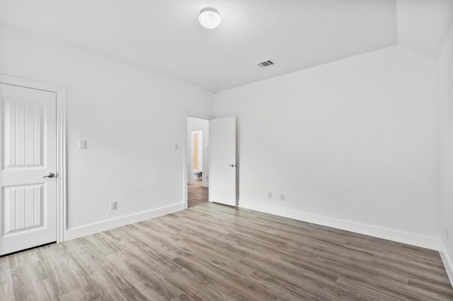 spare room featuring baseboards, wood finished floors, and visible vents