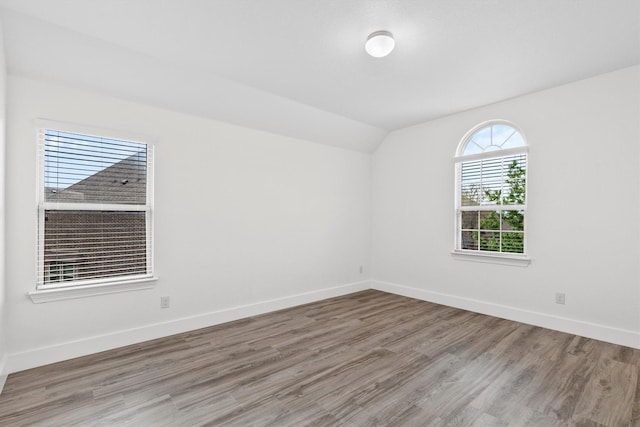 unfurnished room with baseboards, wood finished floors, and lofted ceiling