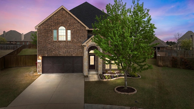 traditional home featuring fence, an attached garage, brick siding, a front yard, and driveway
